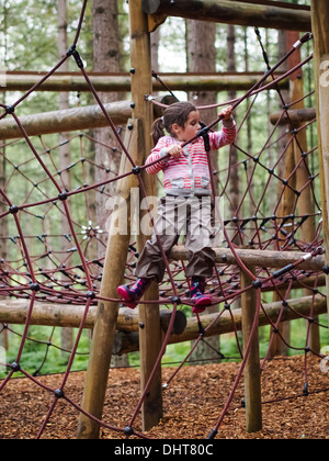 Young girl climbing a rope bridge in an adventure playground Stock Photo