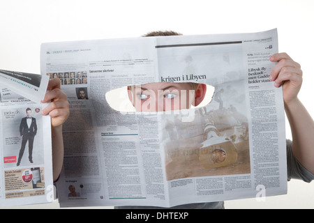 Boy looking through a newspaper hole as a spy Stock Photo