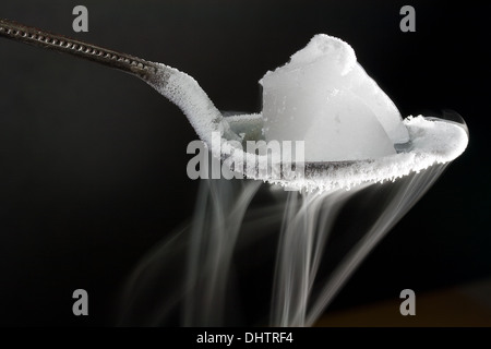 Chunk of Dry Ice (Frozen Carbon Dioxide) on Metal Spoon. Also Shows Water Ice Crystals Forming on the Spoon Stock Photo