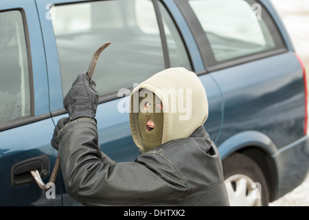 Robber with a crowbar near the car door Stock Photo
