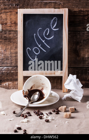 Cup of drunk coffee with chalkboard on table with crumbs and crumpled napkin Stock Photo