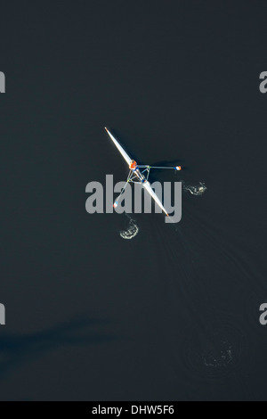 Netherlands, Hilversum, Man rowing in skiff or single scull. A single person propels the boat with two oars. Aerial Stock Photo