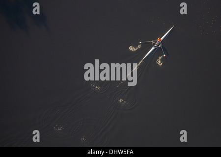 Netherlands, Hilversum, Man rowing in skiff or single scull. A single person propels the boat with two oars. Aerial Stock Photo