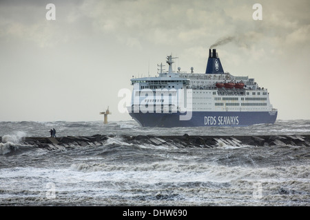 Netherlands, IJmuiden, DFDS ferry arrives from Newcastle during heavy stoL on North Sea. People walk on jetty Stock Photo