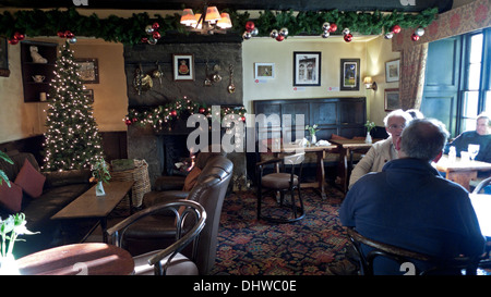 Christmas decorations, people sitting at tables, fire fireplace & tree inside interior of The Bear Hotel in Crickhowell, Powys, Wales UK  KATHY DEWITT Stock Photo