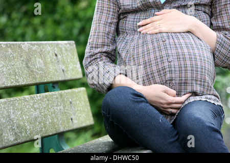 Pregnant woman sitting on a bench. Stock Photo