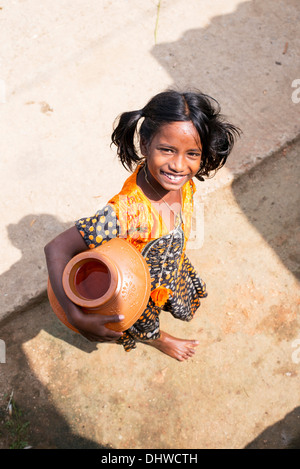 Indian girl carrying a plastic pot with water from a standpipe in a rural Indian village street. Andhra Pradesh, India Stock Photo