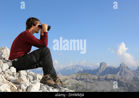 Young man looking through binoculars in the mountains Stock Photo