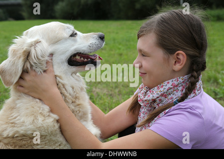 Little girl caressing a dog on a meadow Stock Photo