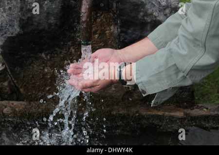 Man putting hands under the tap of a fountain. Stock Photo