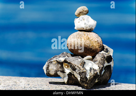 Cairn on the beach in front of blue water Stock Photo