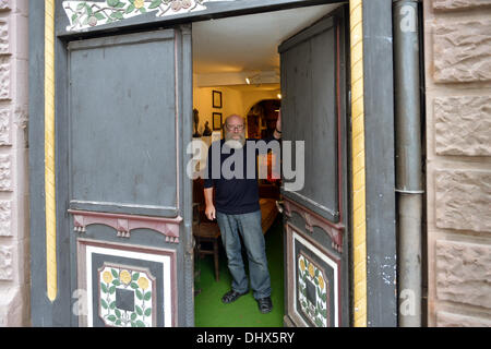 Eisenach, Germany. 07th Nov, 2013. Klaus Trippstein, resident and owner of the 'Narrow House', poses in his house in Eisenach, Germany, 07 November 2013. With a width of 2.05 meters, it is probably the smallest inhabited half-timbered house in Germany. Klaus Trippstein's research has shown that the house is over 250 years old. Klaus Trippstein had bought the house in the mid-seventies and restored it piece by piece. The house hosts a small exhibition of paintings, sculptures and historic furnishings. Photo: Marc Tirl/dpa/Alamy Live News Stock Photo