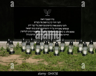 Hebrew inscription on memorial stone in Brzostek Jewish cemetery Poland, memorial lamps placed in front of stone Stock Photo