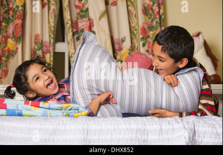 Siblings Enjoying a Pillow Fight Stock Photo