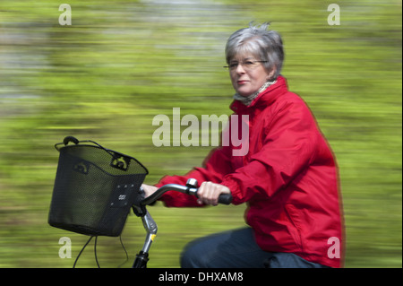 Elderly woman in a red jacket on a bike Stock Photo