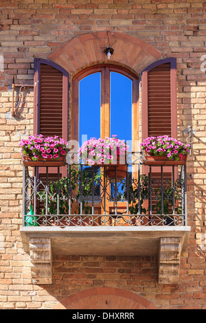 Italian balcony with flowers in San Gimignano. A medieval hill town in the province of Siena, Tuscany Stock Photo