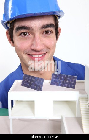 Young worker with an architectural model showing solar panels Stock Photo