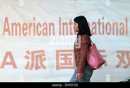 Beijing, CHINA, China. 11th Nov, 2013. A Chinese woman walks past an advertisement for a popular and very expensive international elementary school, specializing in an American curricula, in downtown Beijing on November 11, 2013. The United States and China are tethered together by a complicated economic and strategic relationship - one that is more and more tested due to the current global financial crisis. The two economies are deeply intertwined through trade, capital flow and linked currency exchange rates. © Stephen Shaver/ZUMAPRESS.com/Alamy Live News Stock Photo