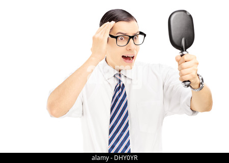 Young worried man checking for thinning hair in the mirror Stock Photo