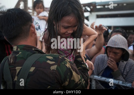 LEYTE, Republic of the Philippines – An Armed Forces of the Philippines soldier helps a child over a fence to be airlifted from Stock Photo