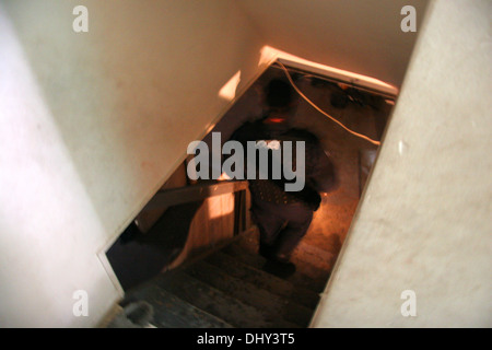 A Detroit Narcotics police officer - Narc - searches the basement of a house during a drugs raid, Detroit, Michigan, USA Stock Photo