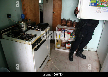 Detroit police Narcotics officer - Narcs - searches a kitchen in a house during a drugs raid Detroit, Michigan, USA Stock Photo