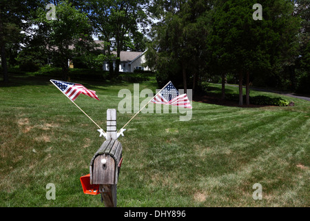 2 American flags on wooden letterbox next to large grass lawn in residential suburb in summer, Gettysburg, Pennsylvania, USA Stock Photo