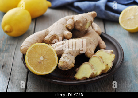 Fresh ginger in plate with lemons on vintage wooden background Stock Photo