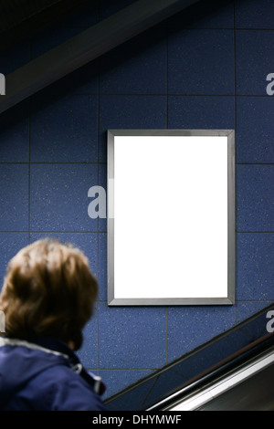 Man looking at blank billboard while climbing on escalator stairs Stock Photo