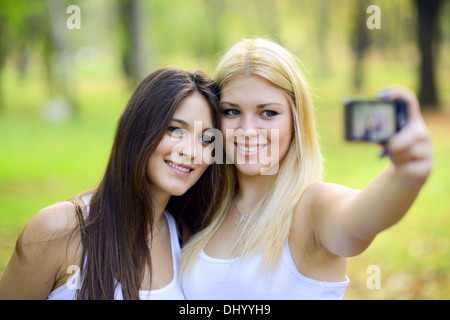 Outdoor portrait of two girl friends taking photos with camera Stock Photo