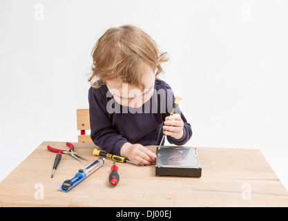 young child opening hard drive with screwdriver Stock Photo