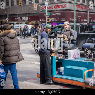 A woman gets her boots shined at a shoe shine stand on Sixth Avenue in New York Stock Photo