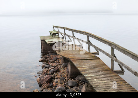 Old ruined wooden pier on the lake in foggy morning Stock Photo