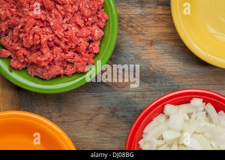 low cholesterol, grass fed, ground buffalo meat and diced onion in colorful ceramic bowls on wood cutting board Stock Photo
