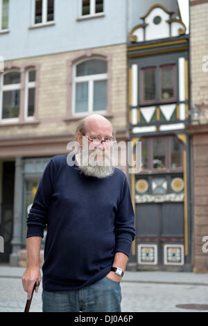 Eisenach, Germany. 07th Nov, 2013. Klaus Trippstein, resident and owner of the 'Narrow House', poses in front of his house in Eisenach, Germany, 07 November 2013. With a width of 2.05 meters, it is probably the smallest inhabited half-timbered house in Germany. Klaus Trippstein's research has shown that the house is over 250 years old. Klaus Trippstein had bought the house in the mid-seventies and restored it piece by piece. The house hosts a small exhibition of paintings, sculptures and historic furnishings. Photo: Marc Tirl/dpa/Alamy Live News Stock Photo
