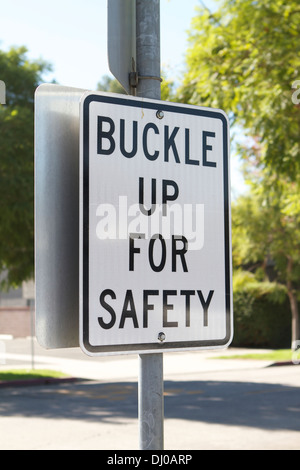 Buckle up for safety sign at the exit of a parking lot to remind drivers to wear their seat belts. Stock Photo