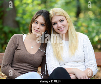 Two teenage girls listening to music outdoors Stock Photo