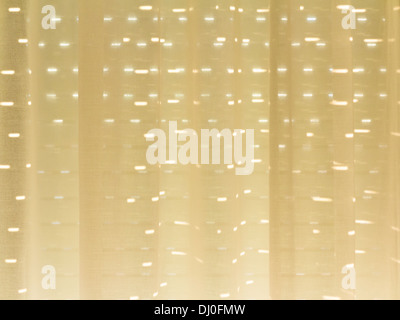 Sunlight through shutters and thin pale yellow curtains Stock Photo