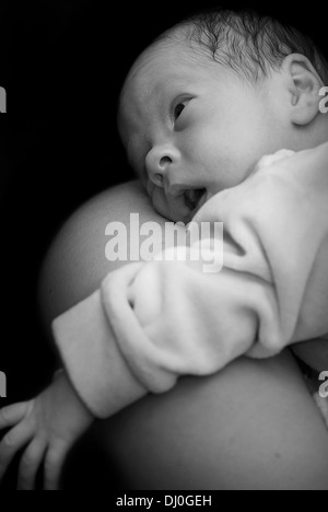 Newborn on mothers shoulder in black and white Stock Photo