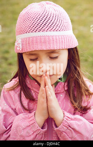 Little girl praying - closeup in the park Stock Photo