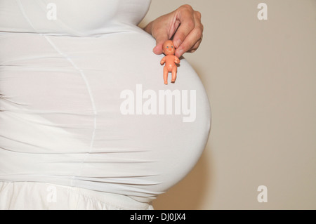 Woman, ninth month pregnancy with doll on belly Model Release Available Stock Photo