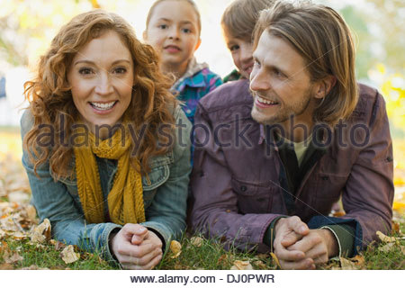 Portrait of happy woman with family lying on grass in park