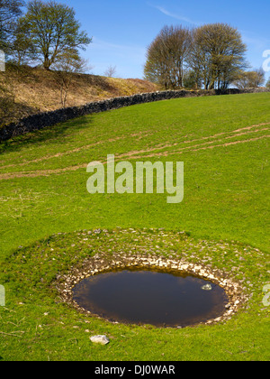 Dew pond used to supply drinking water to livestock on a farm near Hartington in the Peak District Derbyshire England UK Stock Photo