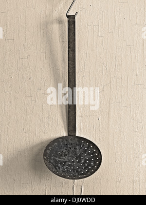 vintage skimmer ladle over old painted yellowish wall Stock Photo