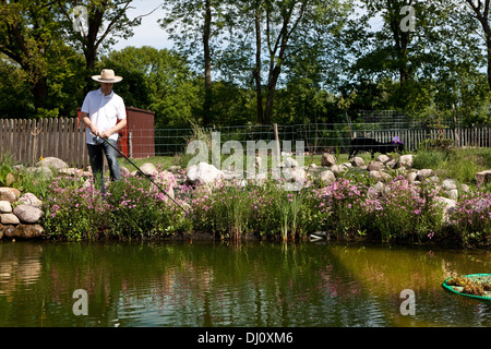 Fishing at the pond. He holds a fishing rod in his hand Stock Photo