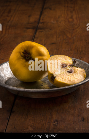 Quinces on metal plate in a still life arrangement with warm lighting on old wooden table Stock Photo