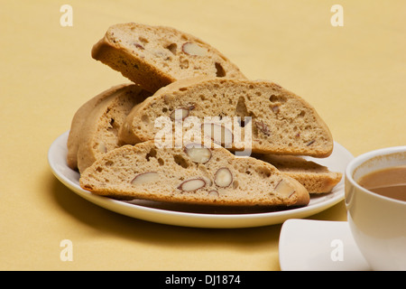 Fresh biscotti with a cup of coffee on yellow background Stock Photo