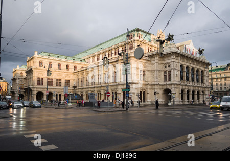 Vienna Opera House and the Ringstrasse at sunset. A damp road highlights the massive stone building. Stock Photo