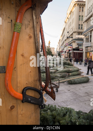 Saws at the Ready on Graben. Swede saws hang on a hut surrounded by just delivered Christmas trees on the main shopping street Stock Photo