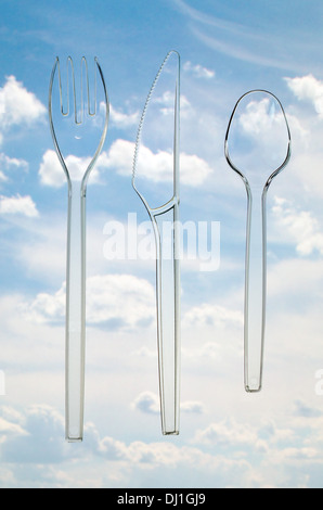transparent plastic cutlery on a background of sky and clouds. Light feed Allegory Stock Photo